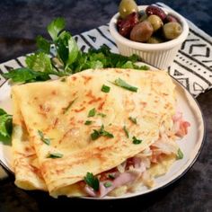 two quesadillas on a plate with olives and parsley next to it