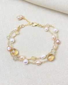 Fall in love with this layered gold bracelet, featuring a stunning combination of pale pink and golden gemstones intricately paired with luminous freshwater pearls. Meticulously handcrafted, this luxe and sophisticated piece is designed to elevate any outfit, whether you're dressing up for a special occasion or adding a touch of elegance to your everyday wear. The seamless interplay of colors and textures creates a visually captivating accessory that truly stands out. Each strand of this layered Delicate Gold Bracelets With Oyster Bracelet, Elegant Pearl Beaded Bracelets With Gemstones, Delicate Gold Oyster Bracelet, Feminine Gold Jewelry For Jewelry Making, Delicate Gold Bracelets With Pearl Charm, Elegant Pearl Bracelets With Natural Stones, Elegant Gold Pearl Bracelet With Natural Stones, Elegant Double Strand Gold Beaded Bracelet, Feminine Gold Jewelry With Round Beads