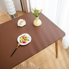 a table with a plate of fruit on it next to a cup and saucer