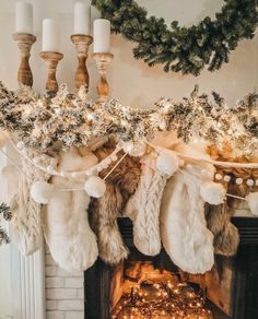 christmas stockings hung over a fireplace with lights and garlands on it's mantle