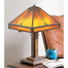 a lamp that is sitting on top of a table next to a book and pen