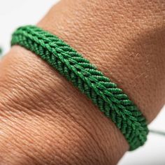 a close up of a person's hand wearing a green bracelet with leaves on it