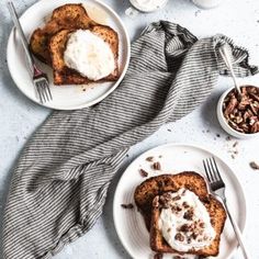 two white plates topped with slices of toast covered in whipped cream and pecanse