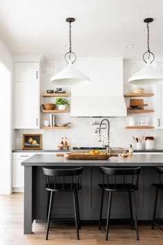 two black chairs are at the center of this kitchen island