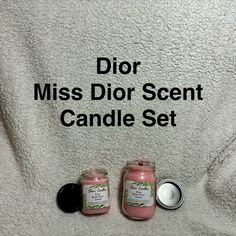 two small candles sitting next to each other on a white towel with the words dior miss dior scent candle set