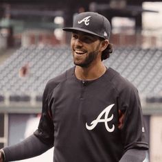 a baseball player smiles as he stands on the field