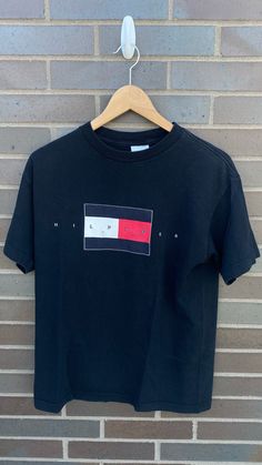 "Vintage 1990s Tommy Hilfiger Black T-Shirt - Size M (Length 26\" Chest 20\") - Overall great vintage condition (no holes or stains) - Message me for more information Please take note of the measurements listed as these are vintage clothes and may fit different than the tag size. Follow our page for more vintage clothing drops! Connect with us on Instagram: @recurarchives" 90s Tommy Hilfiger Outfit, 90s Inspired Black Tops With Screen Print, 90s Inspired Black Screen Print Tops, 90s Inspired Black Cotton T-shirt, 90s Inspired Black Relaxed Fit T-shirt, Tommy Hilfiger Outfits, Polo Tee Shirts, 90s Streetwear, Vintage Polo