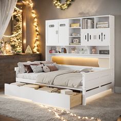 a white bed sitting in a bedroom next to a christmas tree with lights on it