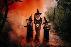 three witches standing in the woods with their hands on their hipss and holding candles