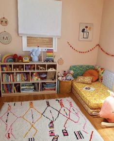 a child's bedroom with pink walls and white rugs on the hardwood floor