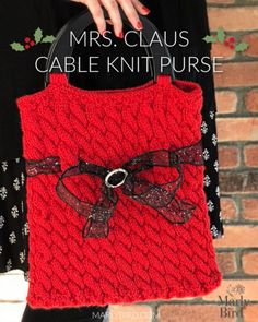 a woman holding a red knitted purse in front of a brick wall with text overlay that says, mrs claus cable knit purse