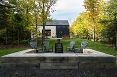 an outdoor fire pit surrounded by chairs and trees