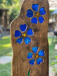 a piece of wood with blue flowers on it and some green grass in the background