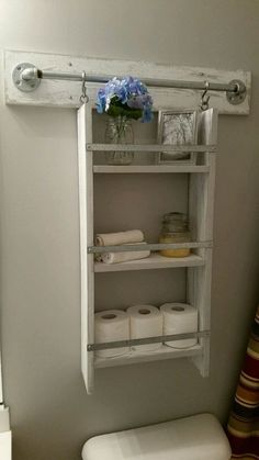 a white toilet sitting in a bathroom next to a wall mounted shelf filled with items