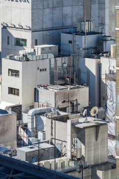 an aerial view of some buildings and rooftops with air conditioning equipment on top, in the city