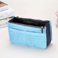 an open blue purse sitting on top of a white table next to books and flowers