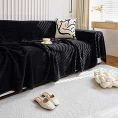 a living room with black couch and white rugs on the floor next to pillows