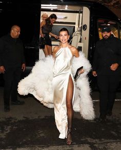 a woman in a white dress is walking down the street