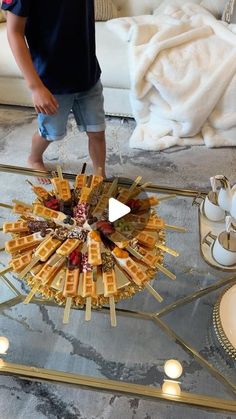 a young boy standing in front of a glass table with food on top of it