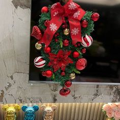 a christmas wreath hanging from the side of a window with ornaments around it and candy canes below