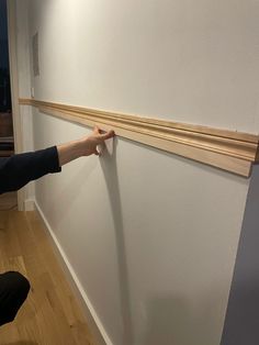 a person is holding the edge of a wall with wood trimmings on it