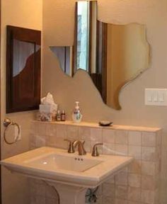 a white sink sitting under a bathroom mirror next to a wall mounted faucet