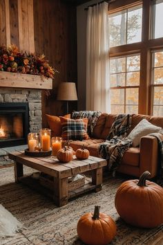 a living room with pumpkins and candles on the coffee table in front of a fireplace