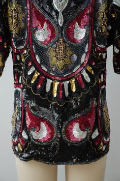 A pure silk shirt with black sequins and beading made in India by Jean for Joseph Le Bon. Very intricate beading completely covers the entire shirt in black, red, and iridescent sequins with beading in silver, iridescent black, red, gold, and iridescent white￼. Gold sunflower details are found on the front, back and sleeves. A pull-on style, it has no closures and is meant to fit loosely. With all of the beading, the weight of the blouse is close to 3 pounds. ☛ m e a s u r e m e n t s ☚ Bust: 39 Hand Embellished Fitted Top For Party, Glamorous Hand Embellished Tops For Party, Glamorous Hand Embellished Party Tops, Silk Party Tops With Sequins, Hand Embellished Fitted Blouse For Party, Fitted Hand Embellished Blouse For Party, Bohemian Short Sleeve Tops For Party, Bohemian Short Sleeve Party Tops, Festival Evening Embroidered Blouse