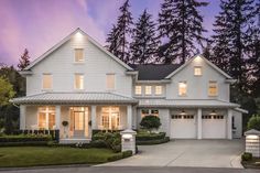 a large white house with lots of windows and lights on it's front porch