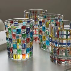 four glass tumblers sitting on top of a table next to a book and pen