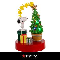 a snoopy christmas tree with presents under it on a red tray next to a yellow star