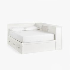 a white bed with two drawers underneath it and a pillow on the bottom half of the bed