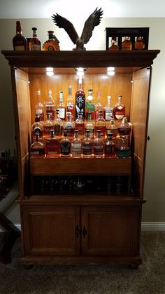 a wooden cabinet filled with lots of different types of liquors on top of it