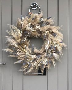 a wreath hanging on the front door of a house with silver and white feathers around it