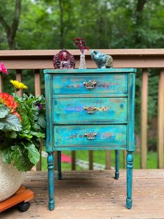 a blue dresser sitting on top of a wooden deck next to a potted plant