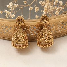 Description: This pair of Nakshi jhumkas exudes divine elegance, featuring the revered Goddess Lakshmi intricately crafted at the center. The detailed Nakshi work enhances the sacred design, making these jhumkas a timeless symbol of grace and tradition. Perfect for adding a touch of spiritual charm to your traditional ensemble, these jhumkas are both a statement of devotion and refined artistry. Product Information: Materials used: 925 Silver with Antique Gold Plating Stones: High Grade CZ Stone Nakshi Jhumkas Gold Earrings, Gold Jhumka Earrings Indian Bridal, Gold Jumkas Antiques, Jumkas Antiques, Nakshi Jhumkas, Gold Jhumka Earrings Bridal, Symbol Of Grace, Silver Jhumkas, Gold Jhumka