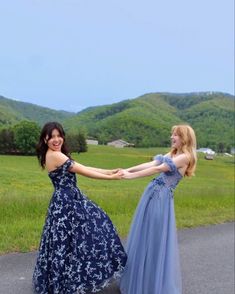 two women in dresses holding hands on the road