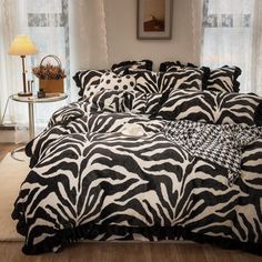 a zebra print comforter set on a bed in a room with white walls and windows