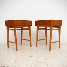 two wooden side tables sitting next to each other on top of a white floor covered in dirt