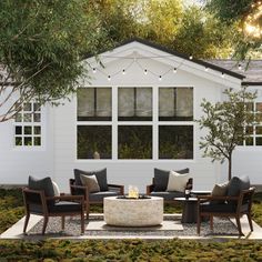 an outdoor living area with furniture and lights on the windows, surrounded by greenery