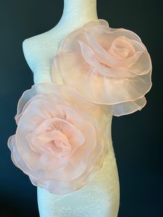 two large pink flowers on top of a white mannequin's torsos