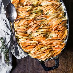 a casserole dish with carrots, cheese and herbs in it on a wooden table