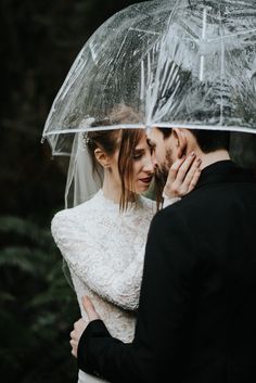 a bride and groom standing under an umbrella