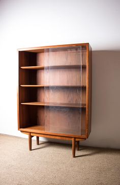 a wooden bookcase sitting on top of a carpeted floor next to a white wall