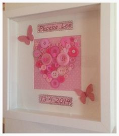 a white frame with pink buttons and butterflies on the inside, in front of a wall