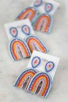 three pairs of colorful beaded earrings sitting on top of a white card with an envelope