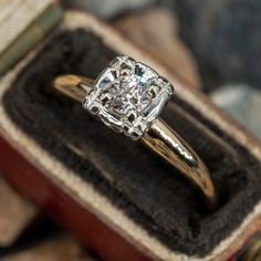 a close up of a diamond ring in a box with other jewelry items around it