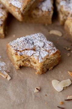 several pieces of dessert sitting on top of a piece of parchment paper with almonds