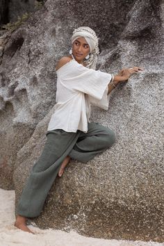 a woman sitting on top of a large rock