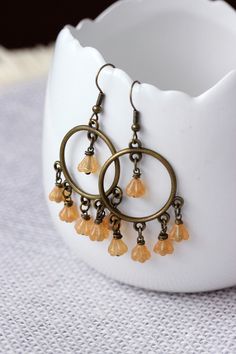 These lovely feminine boho earrings was made of yellow-brown czech glass flower shape beads, antique  brass round chandelier charms, brass jumping rings and antique brass earring hooks. Earring hooks are from nickel free and lead free metal. Perfect jewelry for your unique look or a great gift for someone special! *The total lenght of earrings is about 60 mm including earring hooks. Other earrings of my shop you can see here: https://www.etsy.com/shop/NaTavelli?section_id=13757927  Thanks for vi Bohemian Czech Glass Dangle Flower Earrings, Yellow Bohemian Nickel-free Flower Earrings, Brown Dangle Flower Earrings, Bohemian Brown Dangle Flower Earrings, Bohemian Amber Dangle Earrings, Yellow Bohemian Metal Earrings, Bohemian Gold Flower Bead Earrings, Bohemian Gold Flower Earrings With Round Beads, Bohemian Yellow Dangle Chandelier Earrings